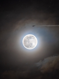 Очень красивая луна светящаяся в ночном небе и самолёт пролетает